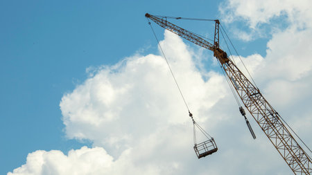 boom of a tower crane against a blue sky, with a construction cradle, backgrounds