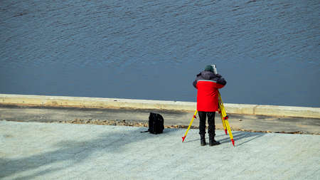 a worker with a tool measures the water level on the riverの写真素材