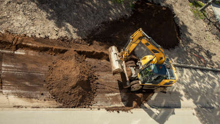 yellow construction excavator throws the earth onto a flower bed,の写真素材