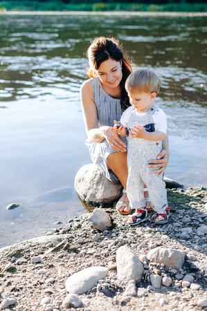 Young family on the walk with his son near the river. Mom plays with her son by the riverの写真素材