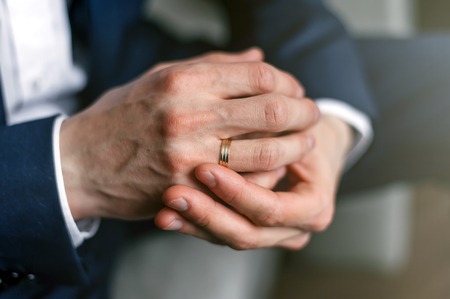 Hands of the groom with an engagement ring. Folded man's hands.の写真素材