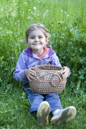 Little girl with basket on the grassの写真素材