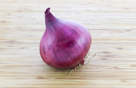 A whole red onion on wooden backgroundの写真素材