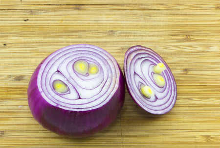 Red onion on chopping board made of woodの写真素材