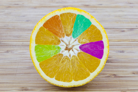 Slice of orange with colorful interior on wooden backgroundの写真素材