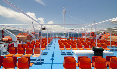 Empty orange chairs on the deck of the ferryの写真素材