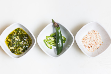 Sesame seeds, pesto sauce and freshly cut chillies on white sauce dippers