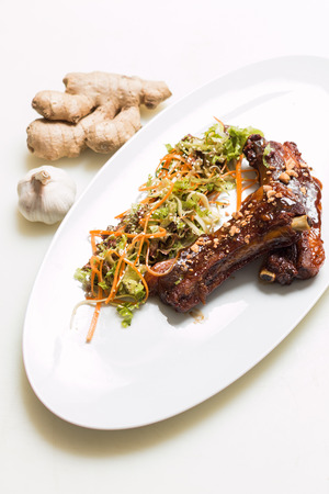 Lamb ribs with sweet sauce with salad dressing on a white plateの写真素材