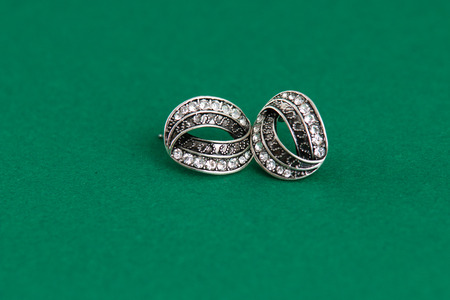 Silver earrings isolated on green background, shot in studioの写真素材