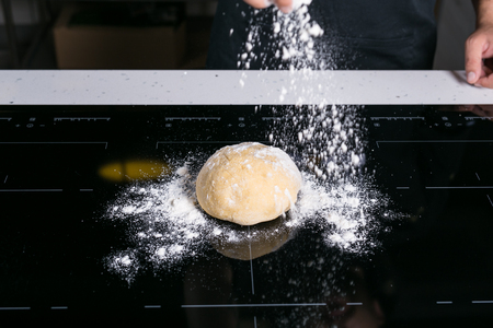 Chef prepairing fresh pasta dough on a black surfaceの写真素材