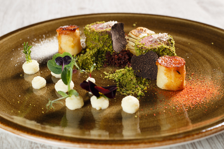 Fine cuisine cooked veal, covered in ground pistachio with truffles on a brown plateの写真素材