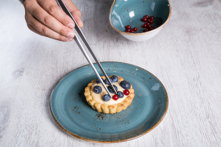 Chef decorating a forest fruit tart on a wooden surfaceの写真素材