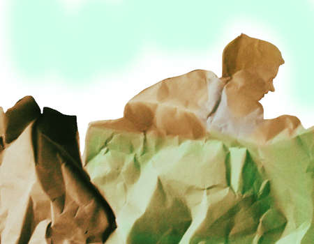 Photo crumpled paper in the form of a little boy sitting in a huge box and looking for somethingの写真素材