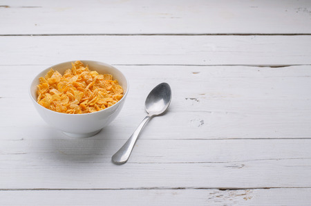 Sports breakfast cereal in a bowl. Diet food, flakes on a wooden table.