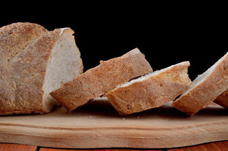 A loaf of fresh bread from the cut pieces on a wooden board. Homemade bread, delicious pastries.