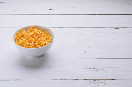 Corn flakes in a plate, healthy breakfast. Diet food, flakes on a wooden table.