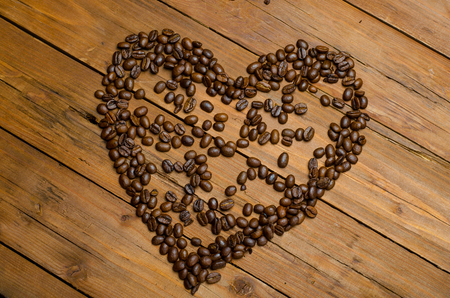 Heart of coffee beans on a wooden table. Symbol of love from coffee beans.の写真素材