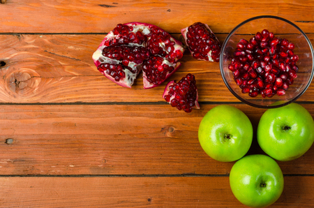 Healthy food: green apple and grenades on a wooden table, space for text. Juicy pomegranate and apples on a wooden background, top view.の写真素材