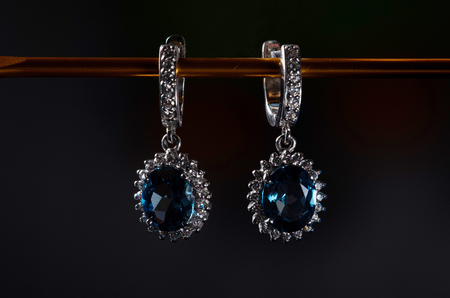 Silver earrings with blue topaz isolated on a black background. Luxury jewelry closeup.の写真素材