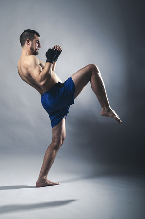Portrait of kickboxer on a gray background. Martial Arts, Sports man kicks.の写真素材