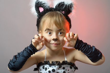 Portrait of a little girl with cat make-up on a gray background. Beautiful girl in carnival costume.の写真素材