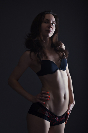 Sexy young woman in black lingerie, closeup. Woman posing on a black background.の写真素材