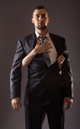A bearded man in a suit and the woman's hand. Stylish man in a suit and tie on gray background.の写真素材