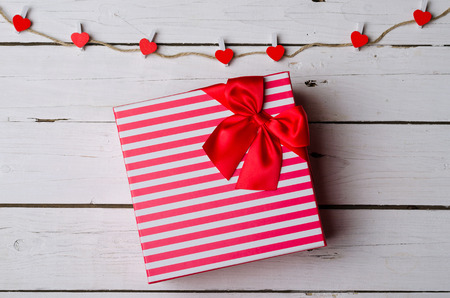 Gift box with a red bow on a wooden background. Love background for Valentine's Day.の写真素材