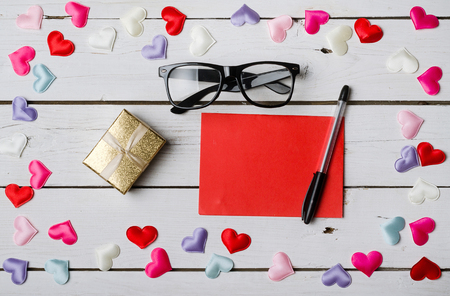 The concept for the day of lovers: a blank sheet of paper, a pen and glasses on a wooden table. Valentine's Day background for a card.の写真素材