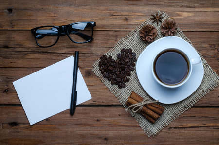 Coffee cup, dessert and spices on an old wooden table, top view. Morning coffee, a sheet of paper, pen and glass on a wooden background.の写真素材