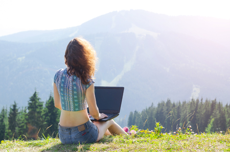 Business woman with laptop on a mountain, copy space. Freelancer works in the outdoors.の写真素材
