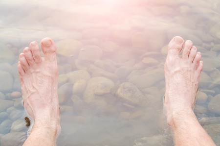 Men's legs in fresh water, mountain river. Camping.の写真素材