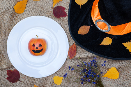 Table setting for halloween: plate, hat of a witch, leaves, top view with copy space. Autumn...