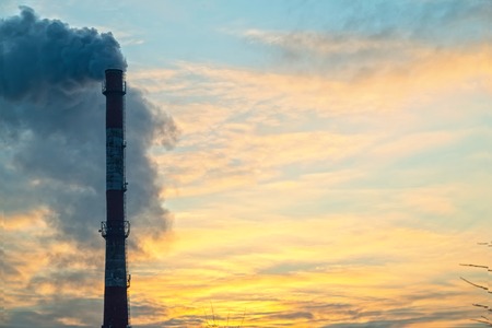 Pipe with smoke on a background of the sky close-up, with copy space. Industrial city, environmental pollution.の写真素材