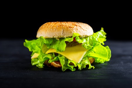 Fresh tasty burger on black background. Appetizing hamburger on the table, a banner for your advertising.の写真素材