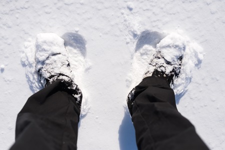 Man standing in the snow, closeup of a foot in a shoe from above. Winter weather, men's feet in shoes.の写真素材