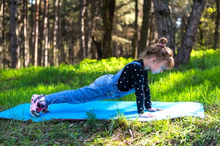 Little girl doing exercise plank, outdoors. Active lifestyle.の写真素材