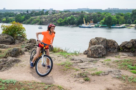 Active lifestyle, young woman on a bike ride. Woman standing with a bicycle, and admire the beautiful scenery.の写真素材