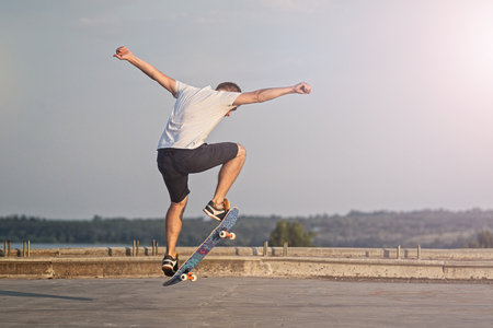 Skateboarder doing an ollie trick on background of blue sky. Active lifestyle.の写真素材