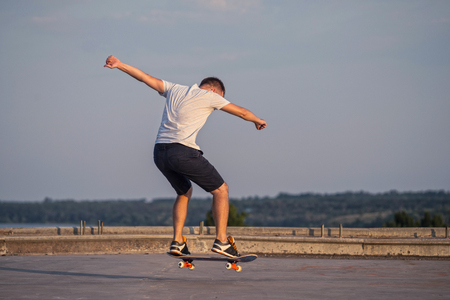 Young skateboarder performing a flip trick in a jump on the road, the free space. The concept of an active way of life.の写真素材