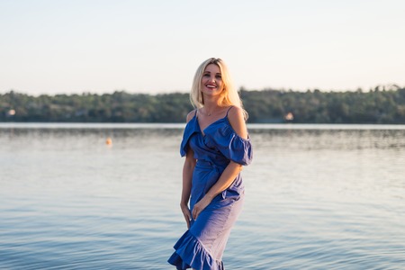 Happy young woman on the river bank, free space. Blonde with long hair outdoors.の写真素材