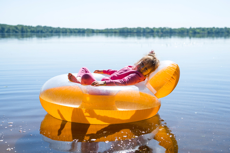 The little girl is resting in an inflatable chair, floating on the water. Vacation travelの写真素材