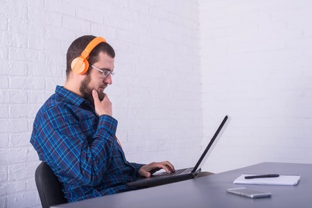 Freelancer working on a laptop in bright headphones, remote work. Office worker working.の写真素材