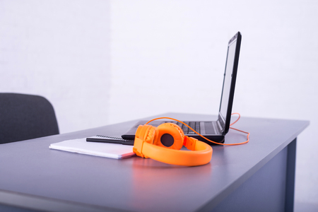 Laptop on the office desk. Workplace: laptop, orange headphones, a notebook and pen.の写真素材