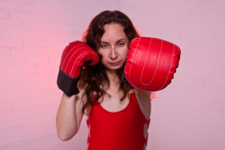 Young woman in red boxing gloves on a pink background. Active lifestyle, self-defenseの写真素材