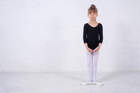 Little girl in the gymnastic swimsuit, free space. The girl trains in the studio.の写真素材