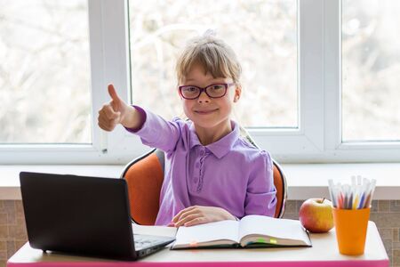 Little schoolgirl is doing homework. The concept of distance learning. Home schooling during...