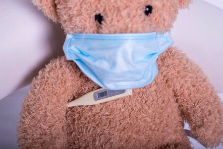 Teddy bear wears a protective medical mask, closeup. Coronavirus. Protection during a pandemic. Heat.の写真素材