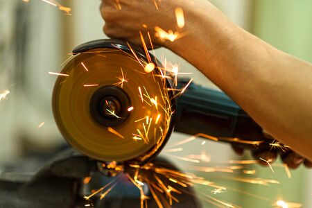 Close-up of a mechanic working as a grinder, sparks fly. Bicycle workshop. Repairs.