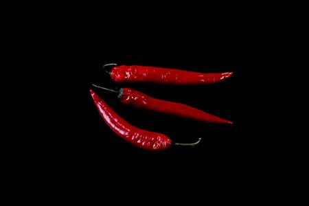 Three pods of fresh chili peppers isolated on a black background. Spice.の写真素材